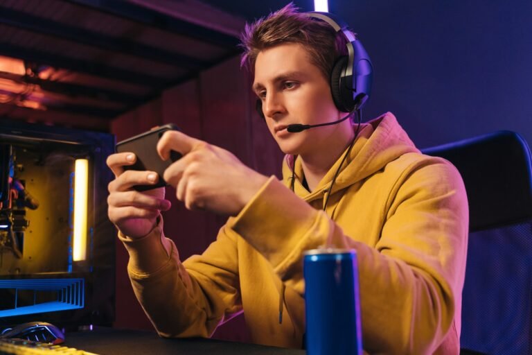 Young pro gamer playing in online mobile video games in neon coloured room